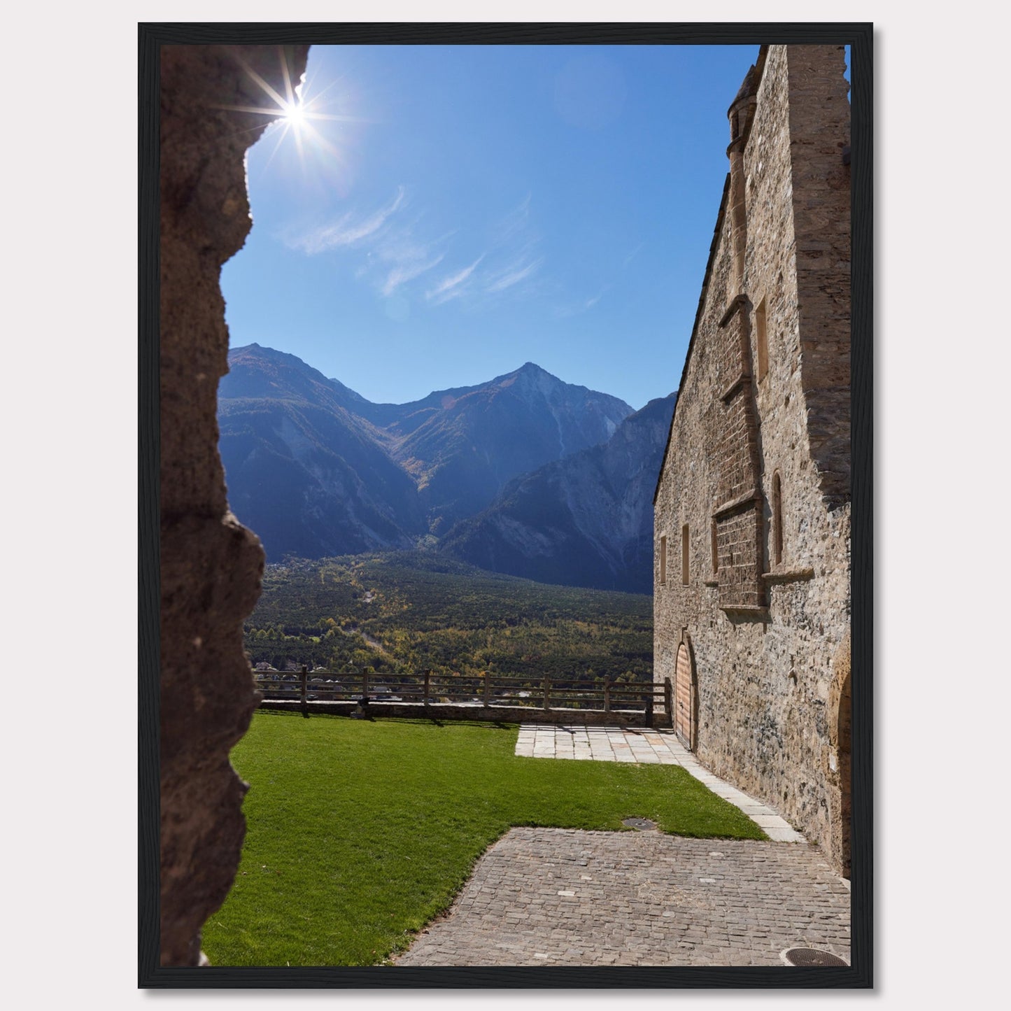 This captivating image showcases a stunning view of a mountainous landscape framed by the rustic stone walls of an ancient structure. The bright sun shines above, casting a warm glow over the scene.