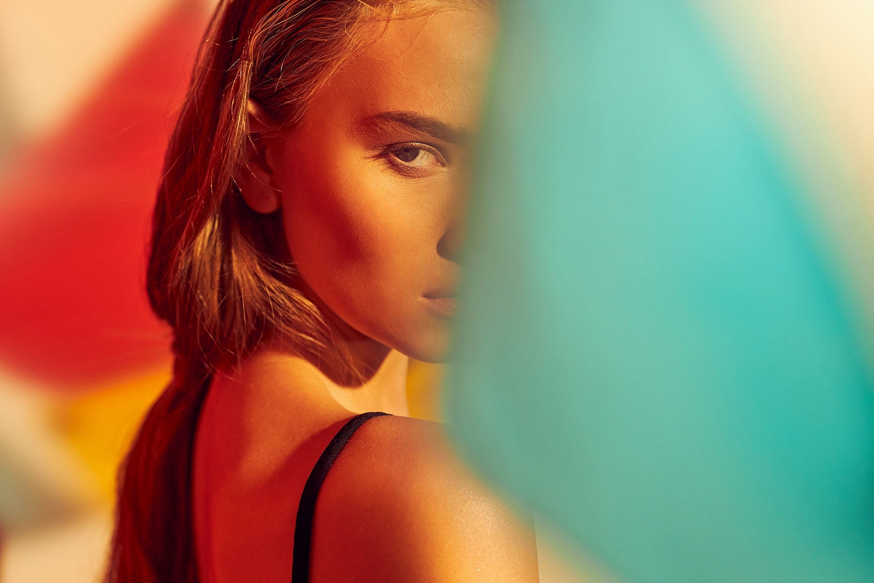 Close-up of a girl with cascading hair, partially obscured by colorful fabrics, showcasing the essence of Art Through the Lens: What is Fine Art Photography?
