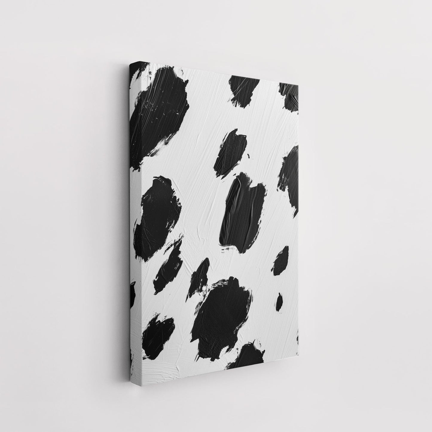 A unique ArtDarts product called "100 and 1 Dalmatians - Canvas" features an abstract pattern of large, irregular black patches, resembling a cowhide print, painted on a rectangular canvas with a white background. The art print is hung on a plain white wall, and the texture of the brush strokes is visible.