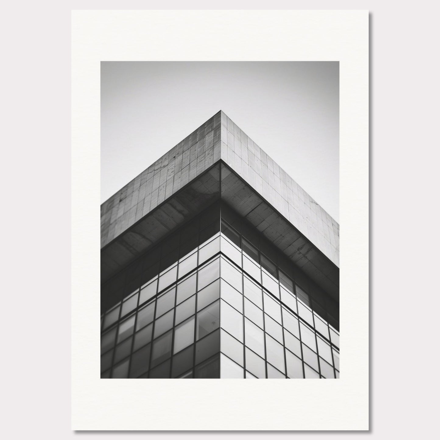 This striking black and white photograph captures the sharp, geometric lines of a modern architectural structure. The image focuses on the corner of a building, emphasizing its sleek glass windows and concrete elements.