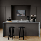 Alpine Winter Rest – Poster in a modern kitchen with black stools and marble countertop, featuring a snowy mountain scene.