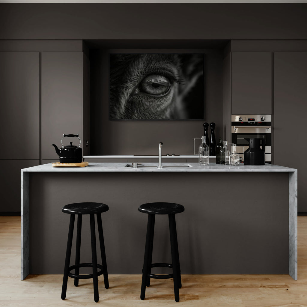 Wolf Eye Reflection – Alu-Dibond wall art displayed in a modern kitchen with marble island and black stools.