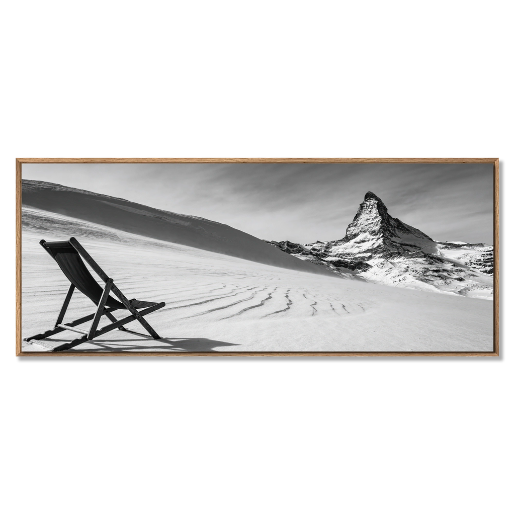 Framed black and white artwork of a mountain and chair on a snowy landscape.