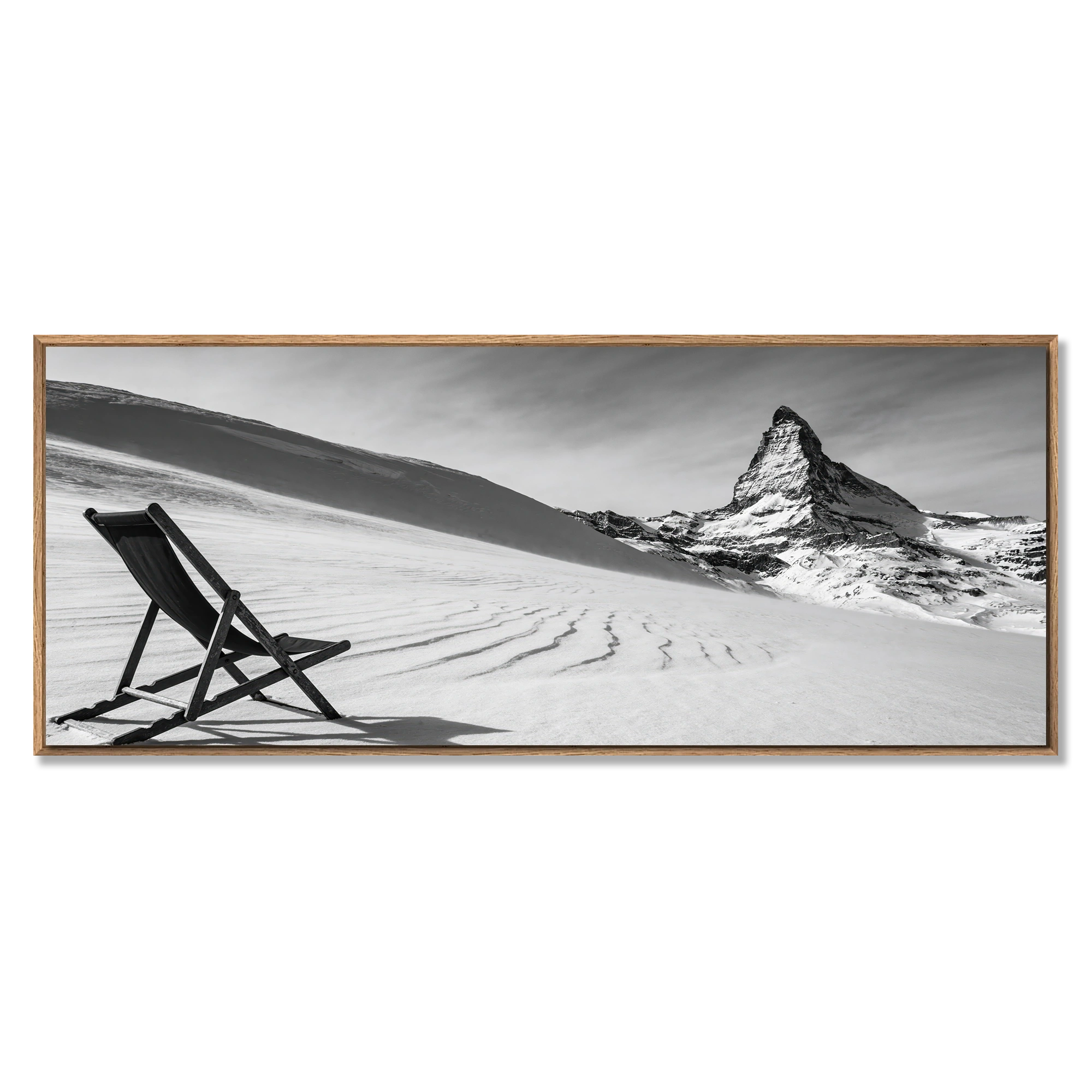 Framed black and white artwork of a mountain and chair on a snowy landscape.