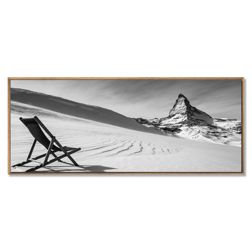 Framed black and white artwork of a mountain and chair on a snowy landscape.