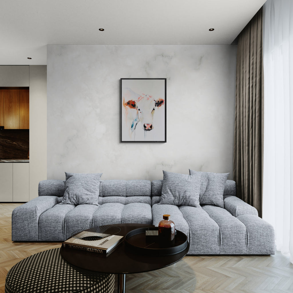 Albino Cow - Poster displayed on wall above a modern gray sectional sofa in a minimalist living room setting.