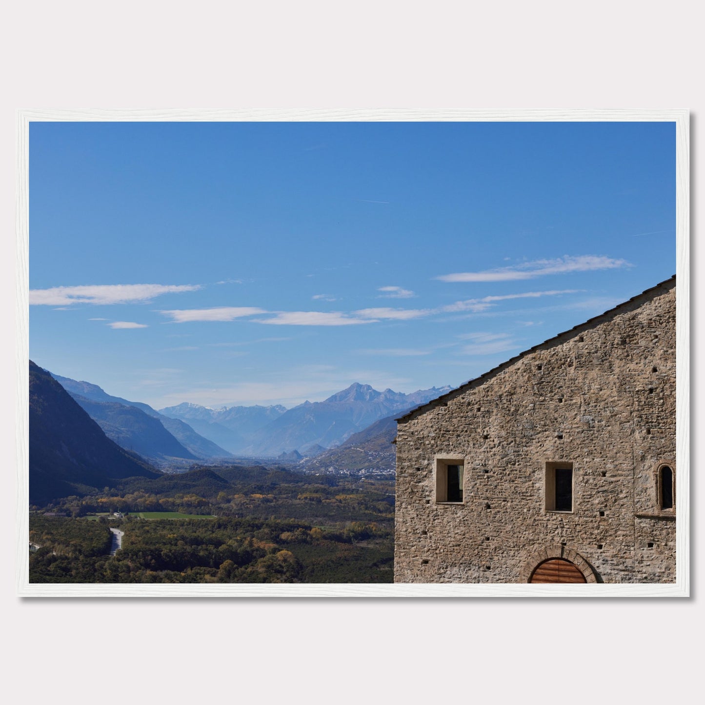 This stunning photograph captures a serene landscape with a historic stone building in the foreground and majestic mountains in the background.