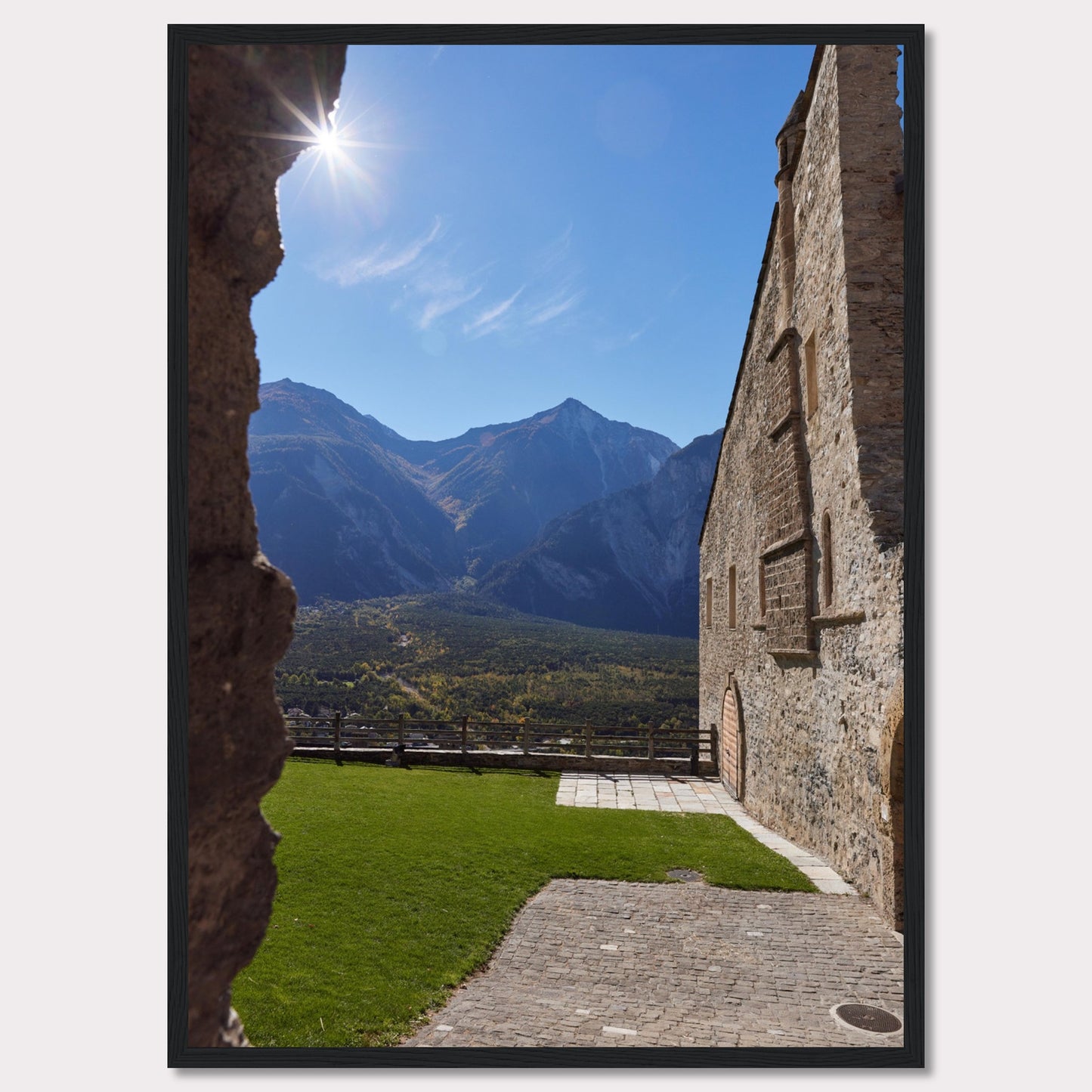 This captivating image showcases a stunning view of a mountainous landscape framed by the rustic stone walls of an ancient structure. The bright sun shines above, casting a warm glow over the scene.