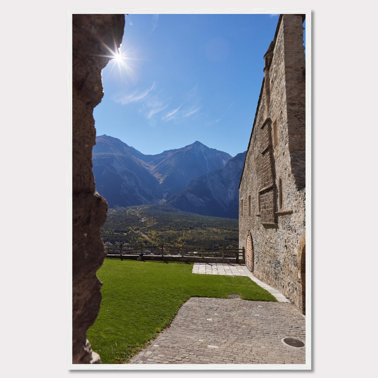 This captivating image showcases a stunning view of a mountainous landscape framed by the rustic stone walls of an ancient structure. The bright sun shines above, casting a warm glow over the scene.