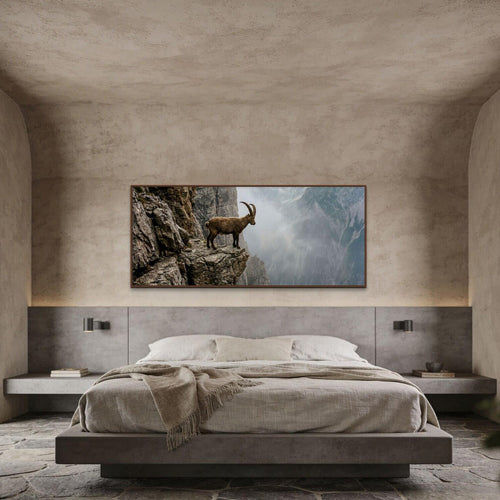 Ibex at the Edge of the Gorge artwork displayed above a minimalist bed in a modern bedroom.