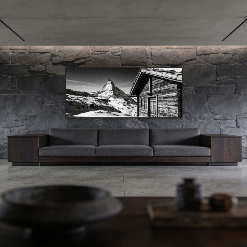 Matterhorn Chalet View – Alu-Dibond wall art displayed in a modern living room with stone wall.