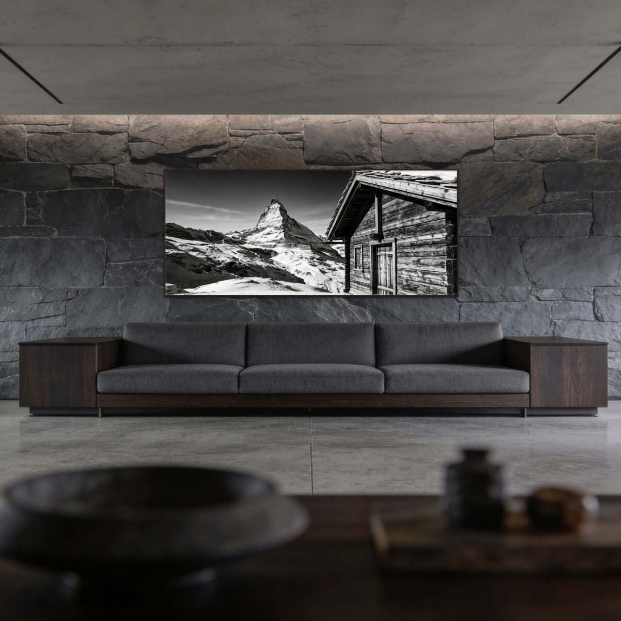 Matterhorn Chalet View – Alu-Dibond wall art displayed in a modern living room with stone wall.