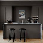 Modern kitchen with marble countertop, featuring a Verbier Skiing - Poster on the wall and stylish black stools.