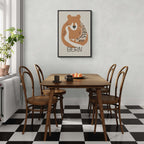 The Bear’s Embrace - Poster displayed in a dining area with a wooden table and chairs, featuring a cozy design.